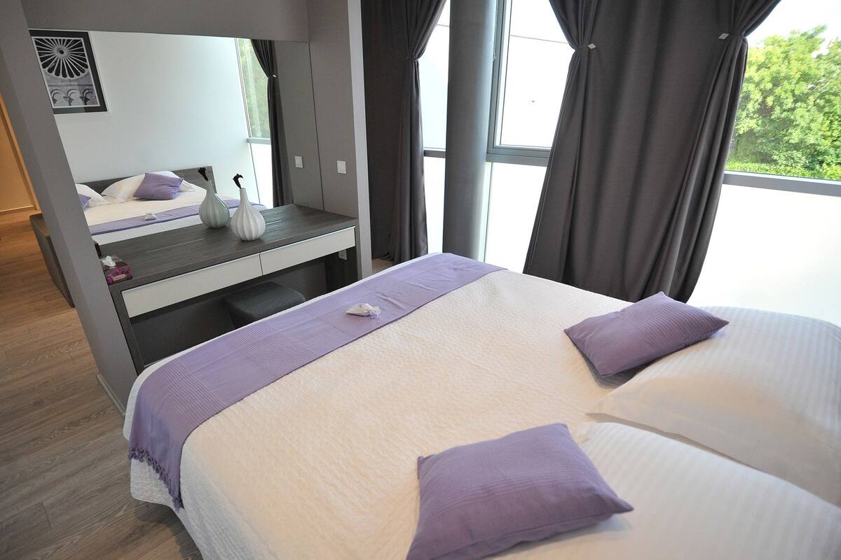 A hotel room with a bed, a desk, and a window.
