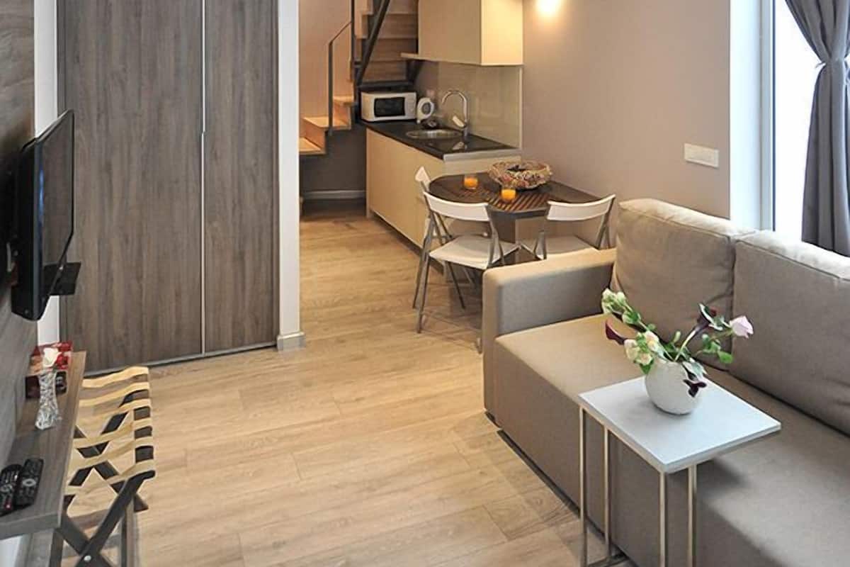 A compact, modern apartment with a loft bedroom, a dining area, and a kitchenette.