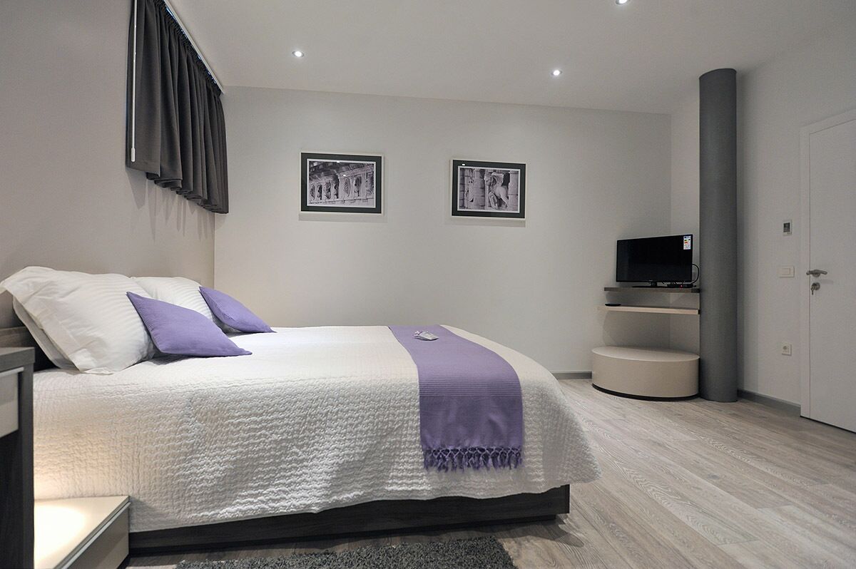A modern bedroom with a bed, a television, and two framed pictures on the wall.