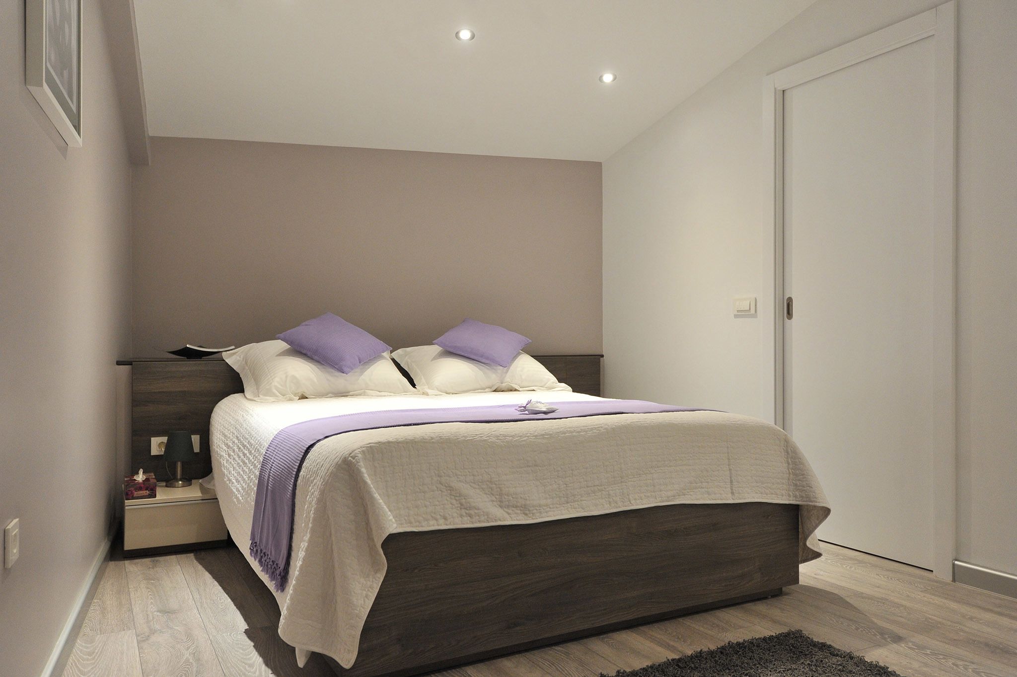 Une chambre à coucher moderne avec un lit, des tables de chevet et une porte.