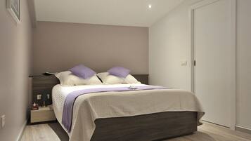 A modern bedroom with a bed, nightstands, and a door.