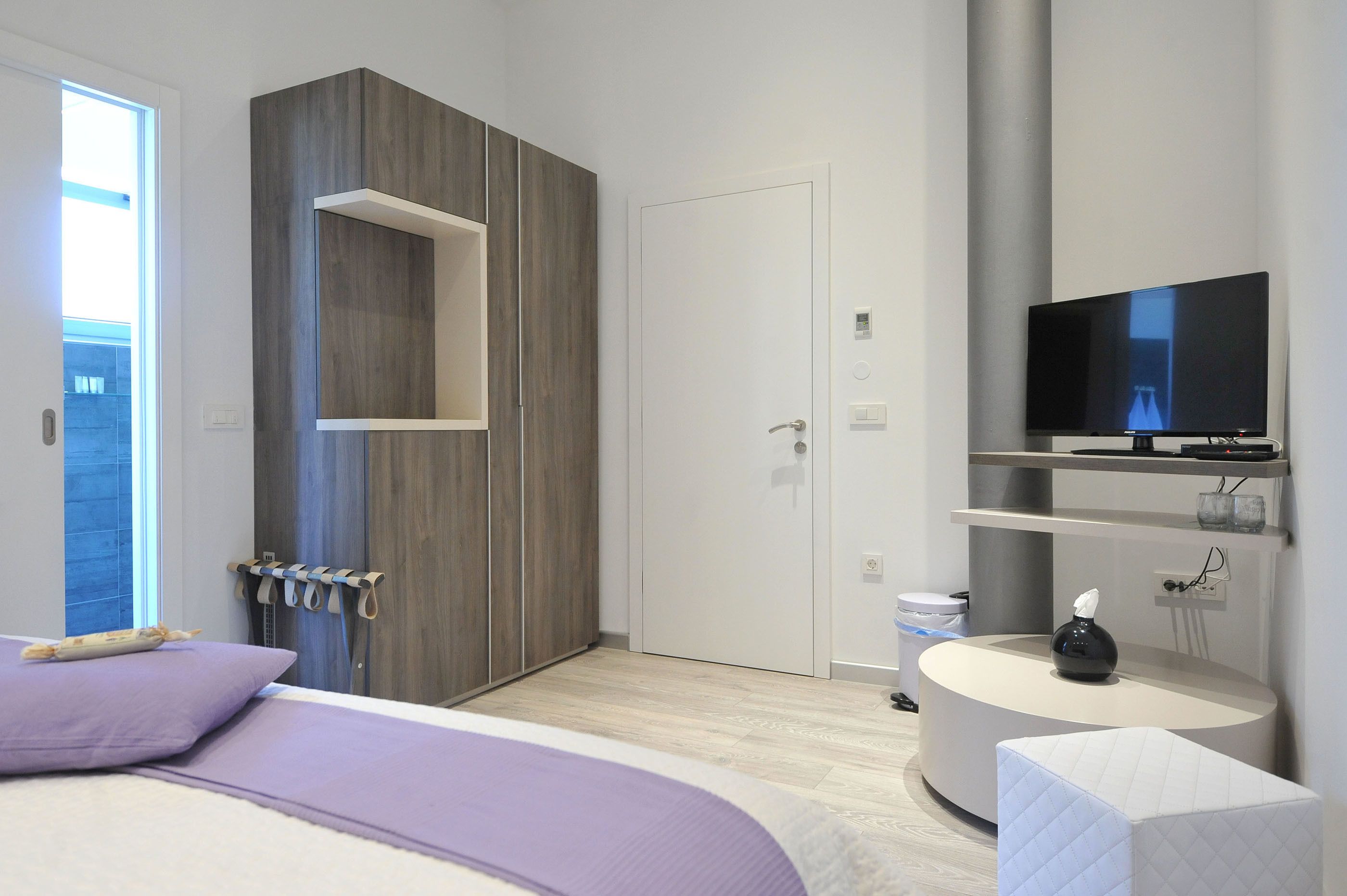Ein modernes Schlafzimmer mit einem Bett, einem Fernseher, einem Nachttisch und einem Kleiderschrank.
