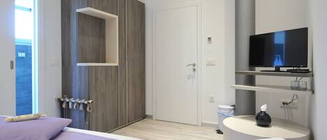 A modern bedroom with a bed, a TV, a bedside table, and a wardrobe.
