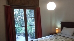 A bedroom with a bed, a nightstand, a lamp, and a window with curtains. - Hostal ByBSiglo (Santiago)