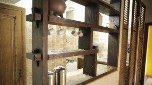 A kitchen with a wooden shelf, hanging mugs, and stainless steel containers. - Hostal ByBSiglo (Santiago)