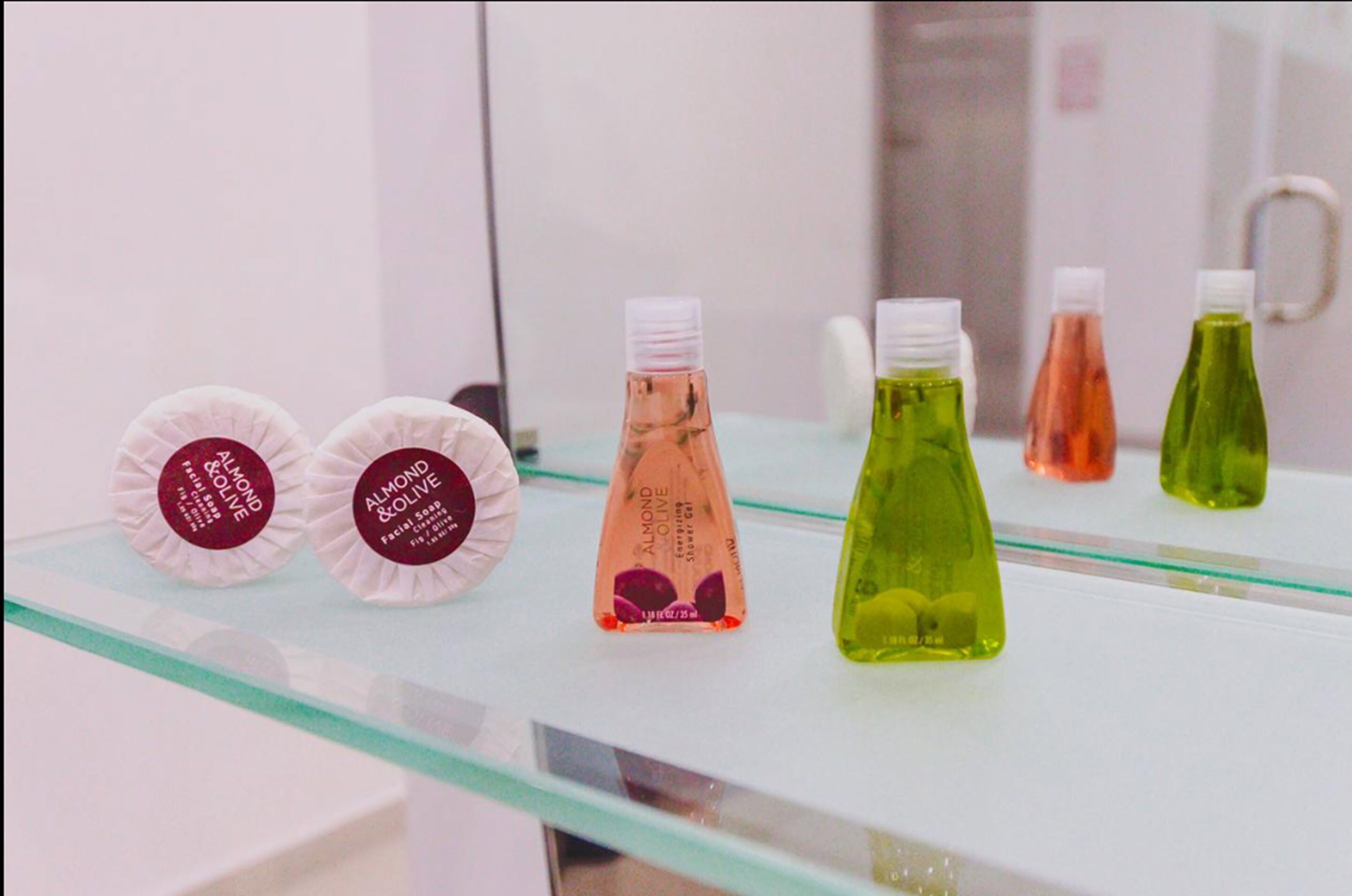 Un baño con una repisa de cristal que exhibe diversos artículos de aseo.
