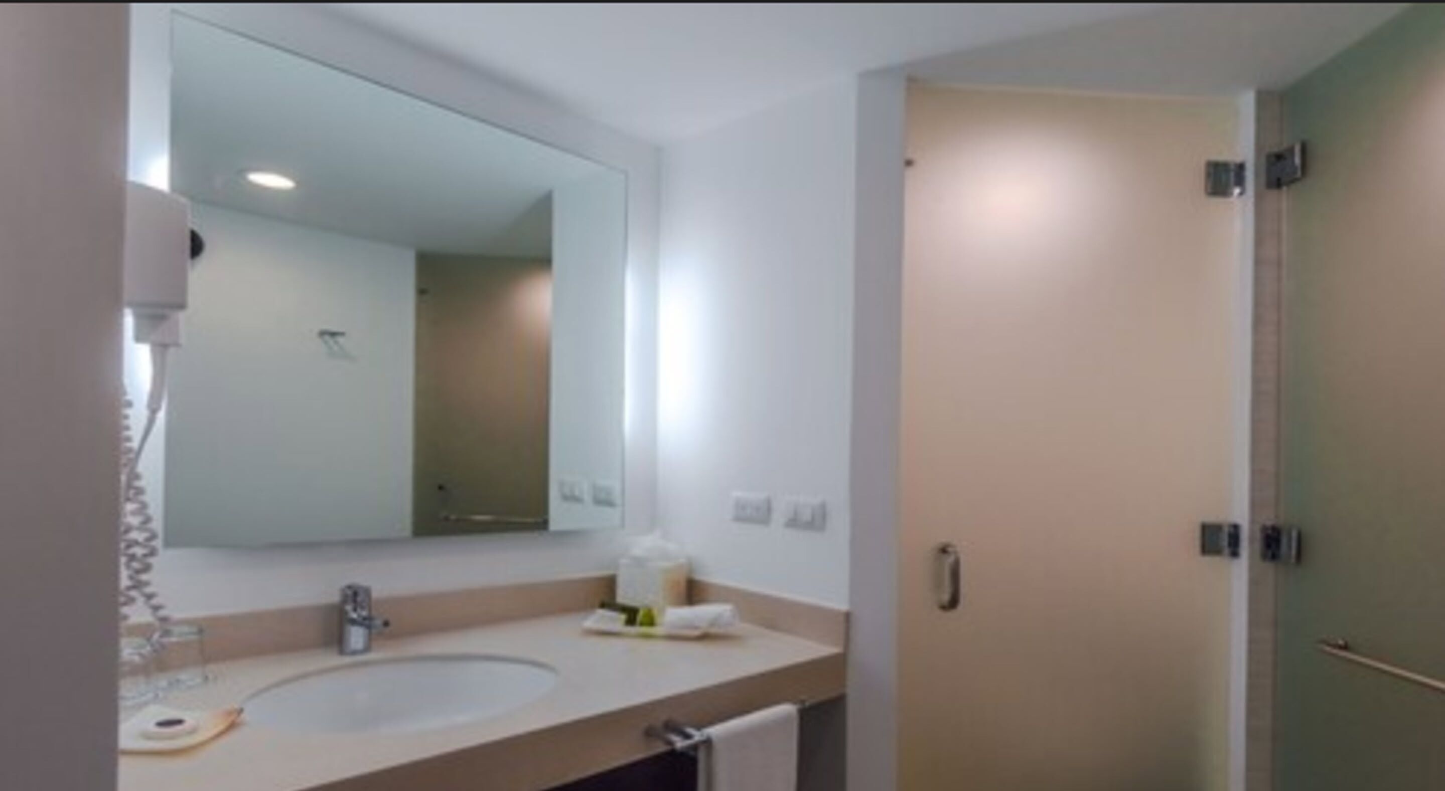 A bathroom with a double sink, a mirror, a towel rack, and a door.