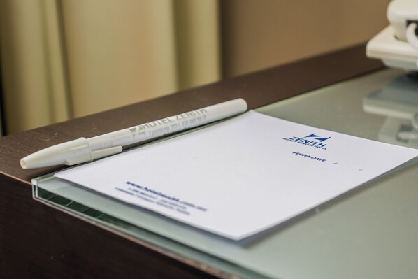 A hotel brochure on a glass table with a pen beside it.