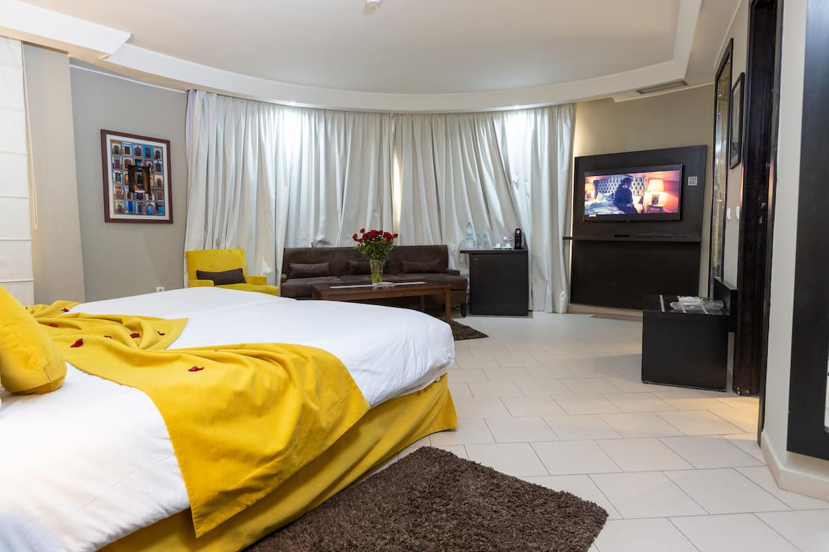 A hotel room with a large bed, a TV, a sofa, and a coffee table.