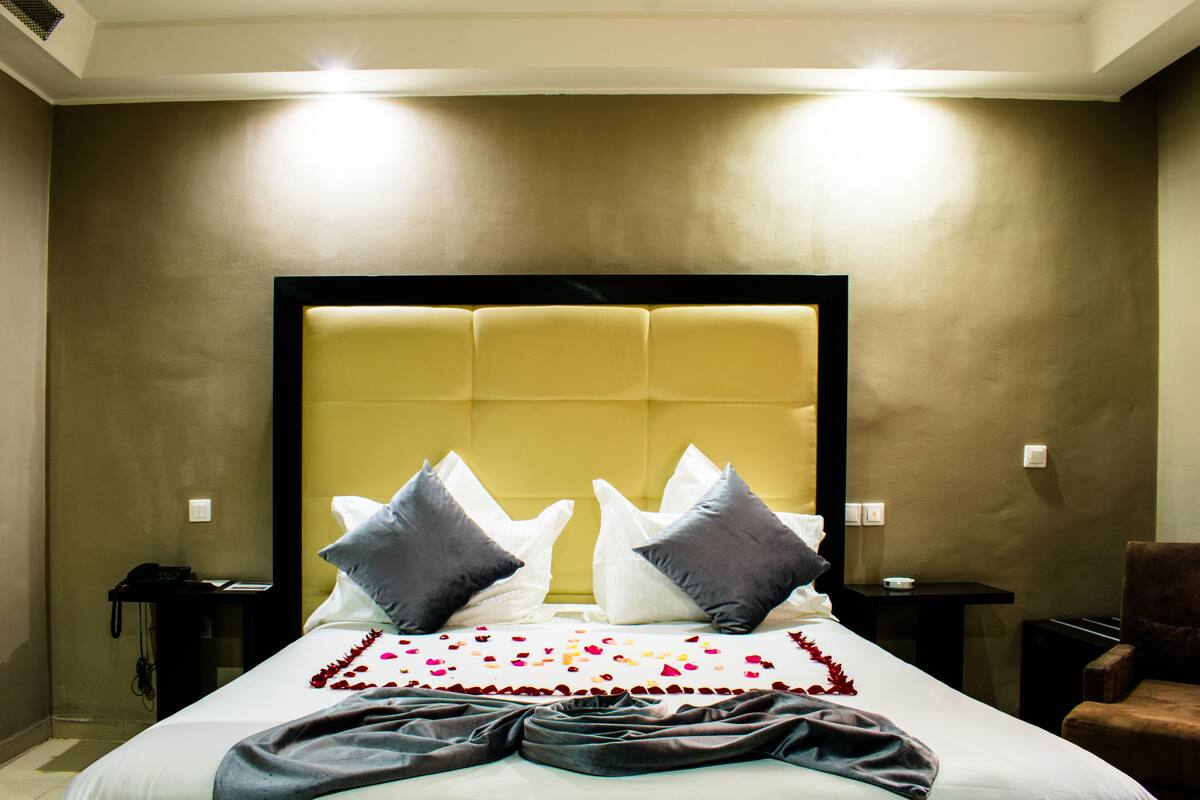 A hotel room with a large bed, a headboard, bedside tables, and a chair.
