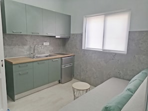 A compact kitchen with a sink, cabinets, and a small round table. - Villa Maria (Parga)