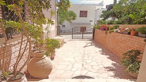 A paved courtyard with potted plants and a gate. - Villa Maria (Parga)