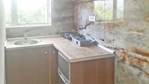 A compact kitchen with a sink, stove, and cabinets. - Villa Maria (Parga)