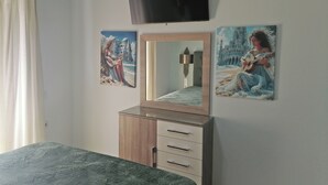 A bedroom with a bed, a dresser, a TV, and three paintings on the wall. - Villa Maria (Parga)