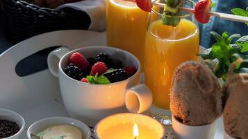 A tray with croissants, fruit skewers, a candle, and various spreads.