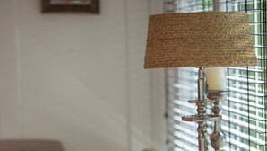 Un comedor ordenado con una mesa preparada para dos personas, que incluye una lámpara, una vela y una decoración con cactus.
