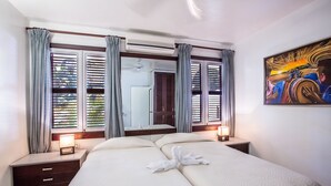 Een hotelkamer met een groot bed, twee nachtkastjes, een spiegel en een schilderij aan de muur.