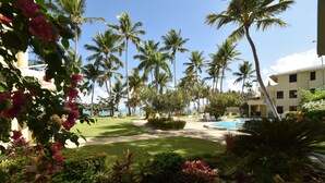 Een resort met een zwembad, palmbomen en een verzorgde tuin.