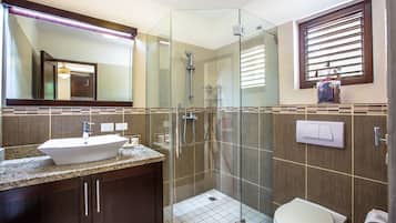 Un baño moderno con ducha de vidrio, lavamanos con encimera de mármol y retrete.