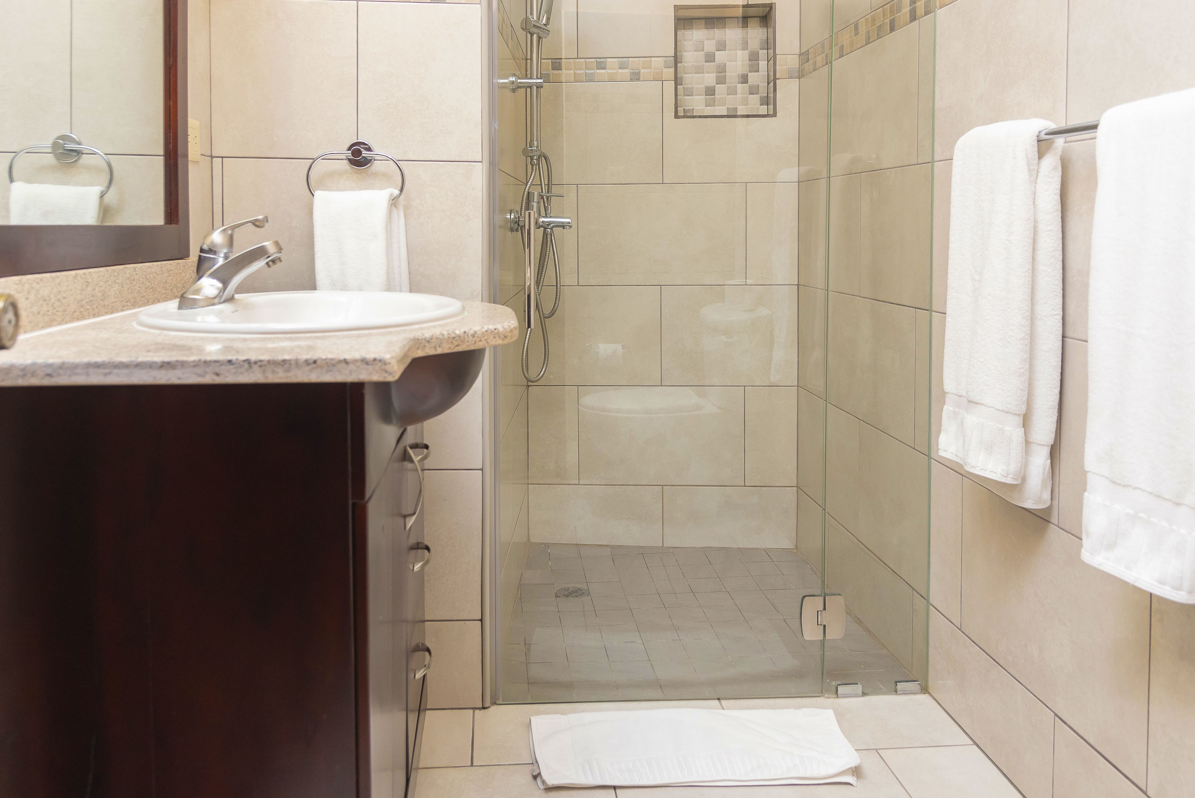 Une salle de bain moderne avec une douche à parois de verre, un lavabo avec un miroir et un porte-serviettes.