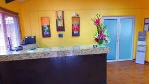 A reception area with a marble counter, a computer, and a vase of flowers. - Hotel Chapala Country (Chapala)