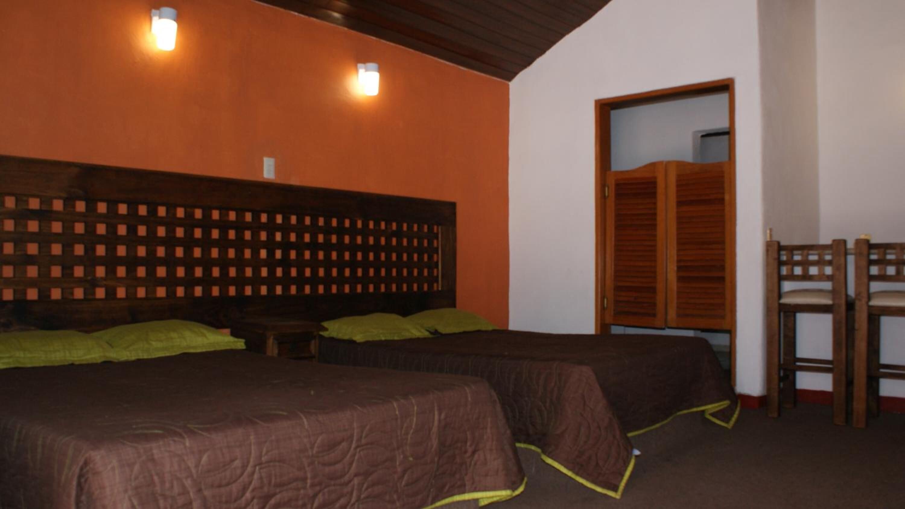 Una habitación con dos camas, cabeceros de madera y un armario de madera.