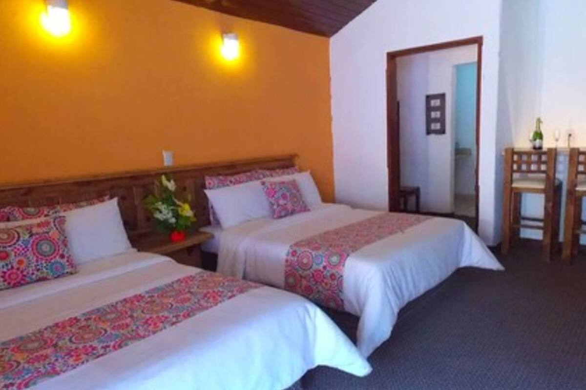 Habitación de hotel con dos camas, una mesita y un espejo.