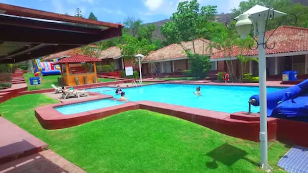 A swimming pool with a slide, a small play area, and a covered seating area.