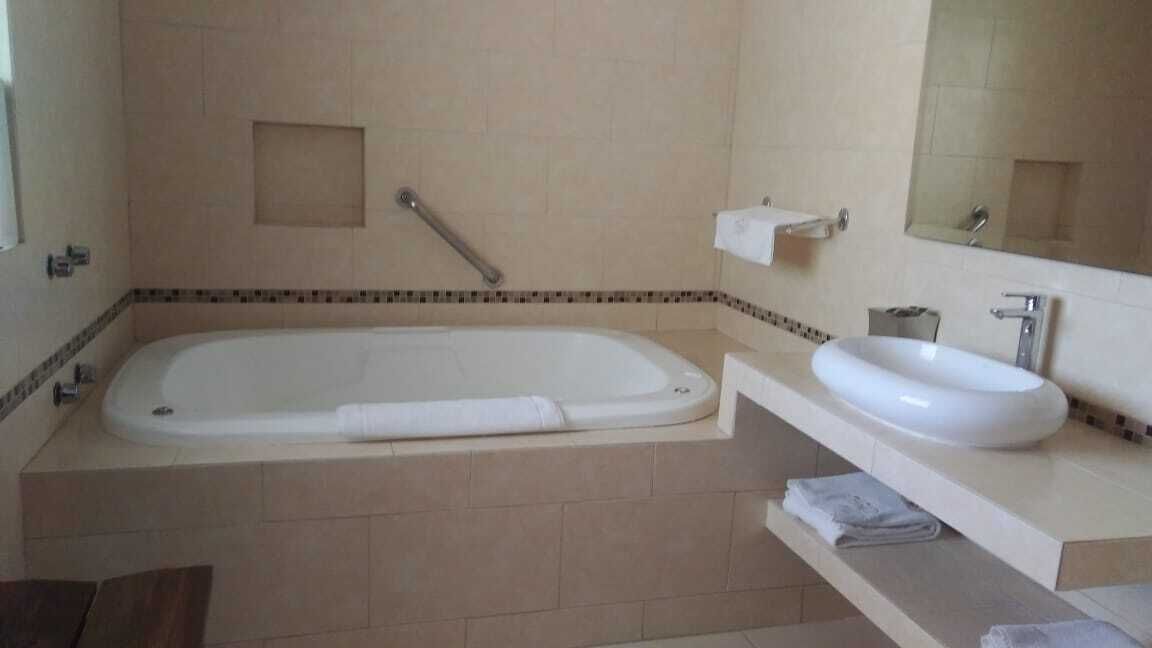 A bathroom with a large bathtub, a sink, and a mirror.