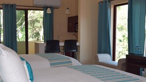 A hotel room with two beds, a desk, a chair, and a television.