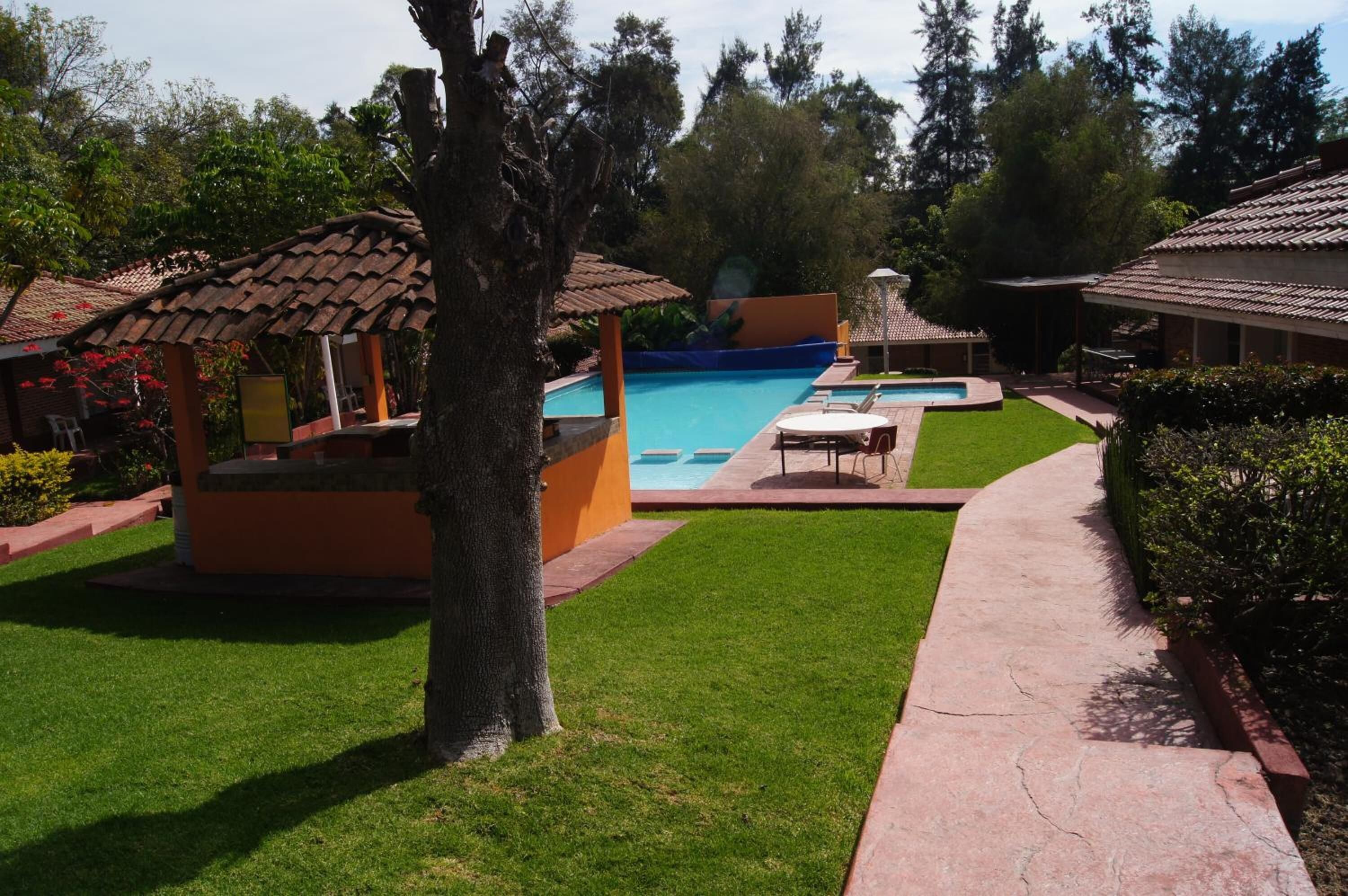 A pool area with a clear blue pool, lounge chairs, and a small gazebo.