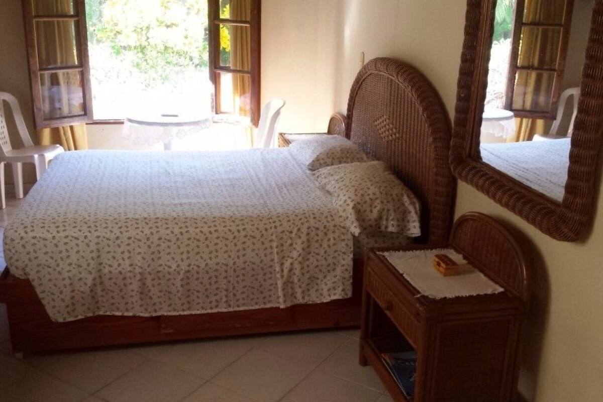 Une chambre à coucher avec un lit, une table de chevet, une chaise et un miroir.