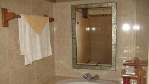 Un baño con un lavamanos blanco, un espejo y una toalla colgada en un perchero.