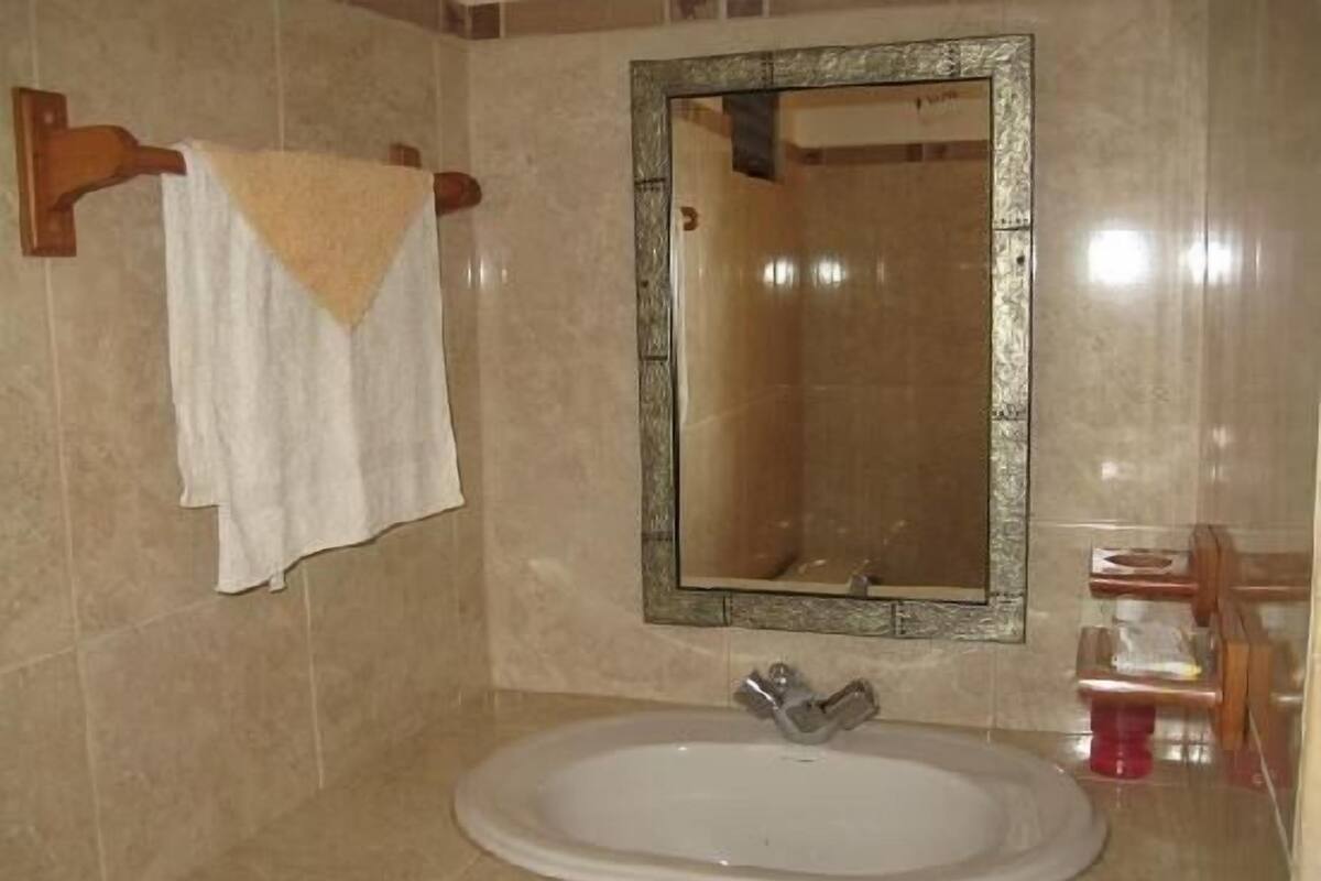 Une salle de bain avec un lavabo blanc, un miroir et une serviette suspendue à un porte-serviettes.
