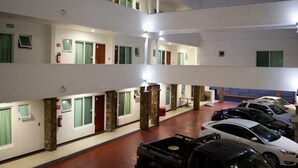 Un hôtel à plusieurs niveaux, avec de nombreux étages, un parking avec des voitures et un extincteur situé au rez-de-chaussée.