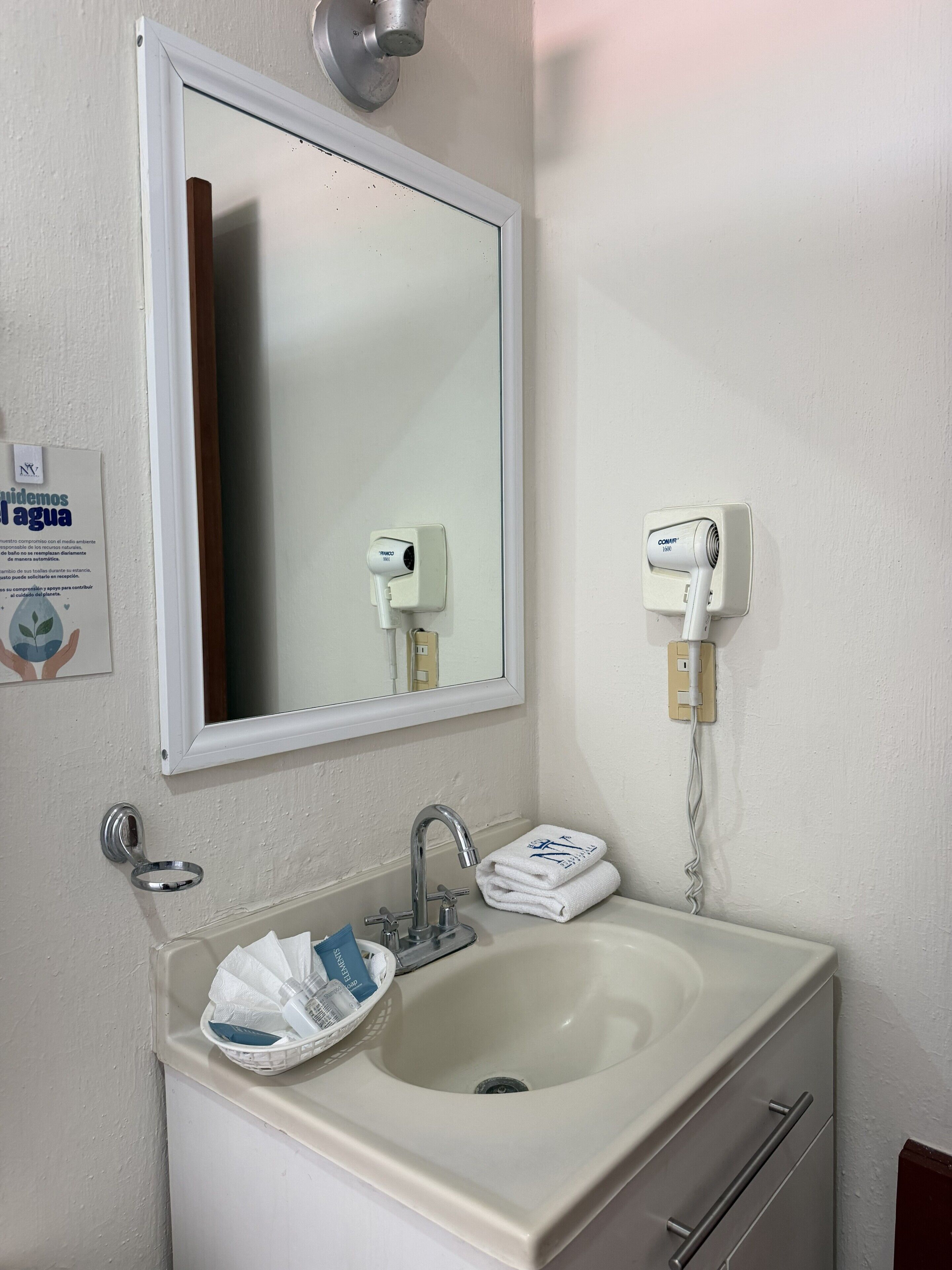A bathroom with a sink, mirror, and two wall-mounted devices.