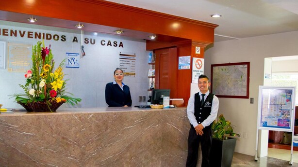 Un comptoir d’accueil avec une pancarte indiquant « BIENVENUE CHEZ VOUS » et un arrangement floral.
