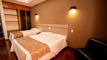 Una habitación de hotel con dos camas, un armario de madera y un sofá de cuero negro.