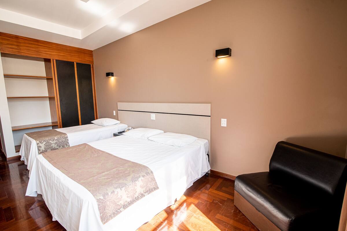Habitación de hotel con dos camas, un sofá y un armario de madera.