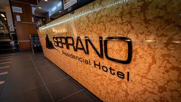 Une enseigne pour l’hôtel SERANO, un établissement proposant des logements, avec un mur texturé en arrière-plan.