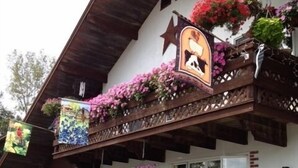 Una cabaña tradicional con techo inclinado, balcones con jardineras y un emblema en forma de estrella.