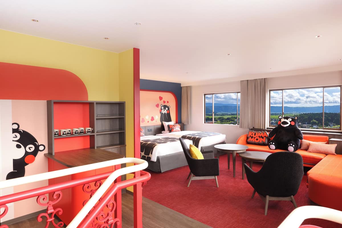 A modern hotel room with a bed, sofa, chairs, and a view of the landscape.