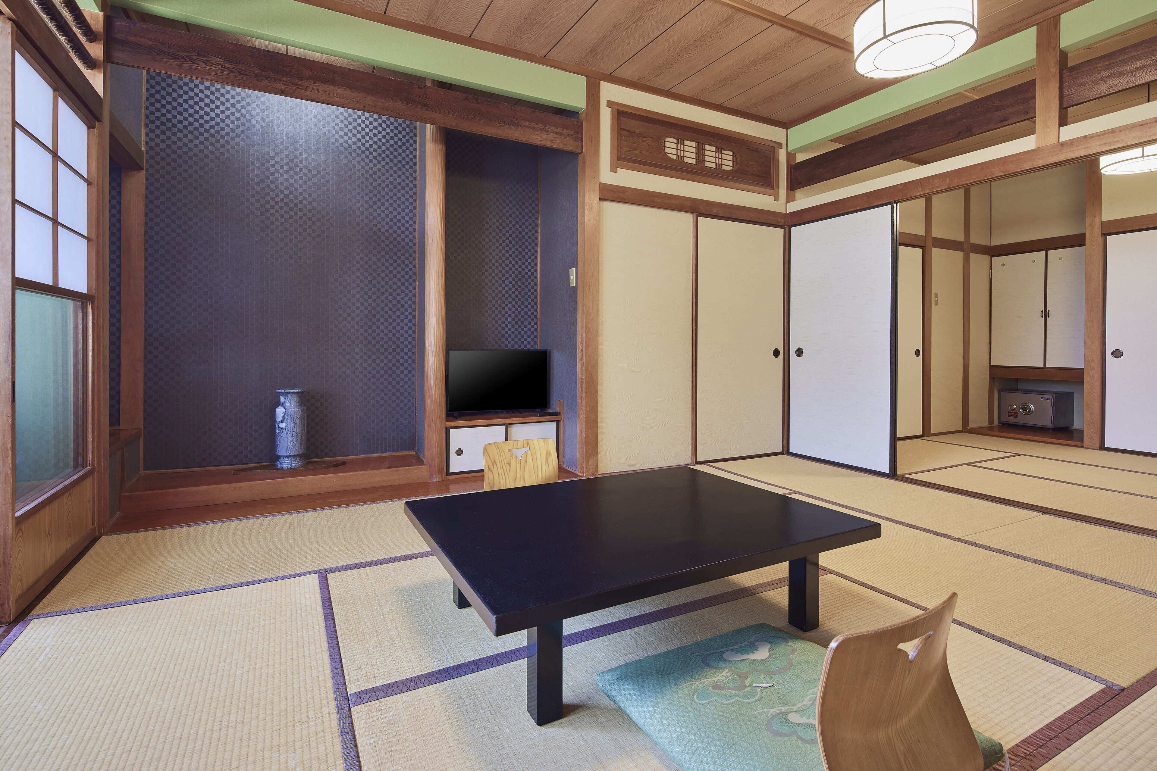 Una habitación japonesa tradicional con suelo de tatami, una mesa baja, televisión, puertas correderas y un armario.