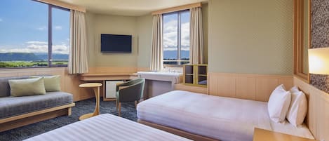 Habitación de hotel con dos camas, un sofá, un escritorio y un televisor.
