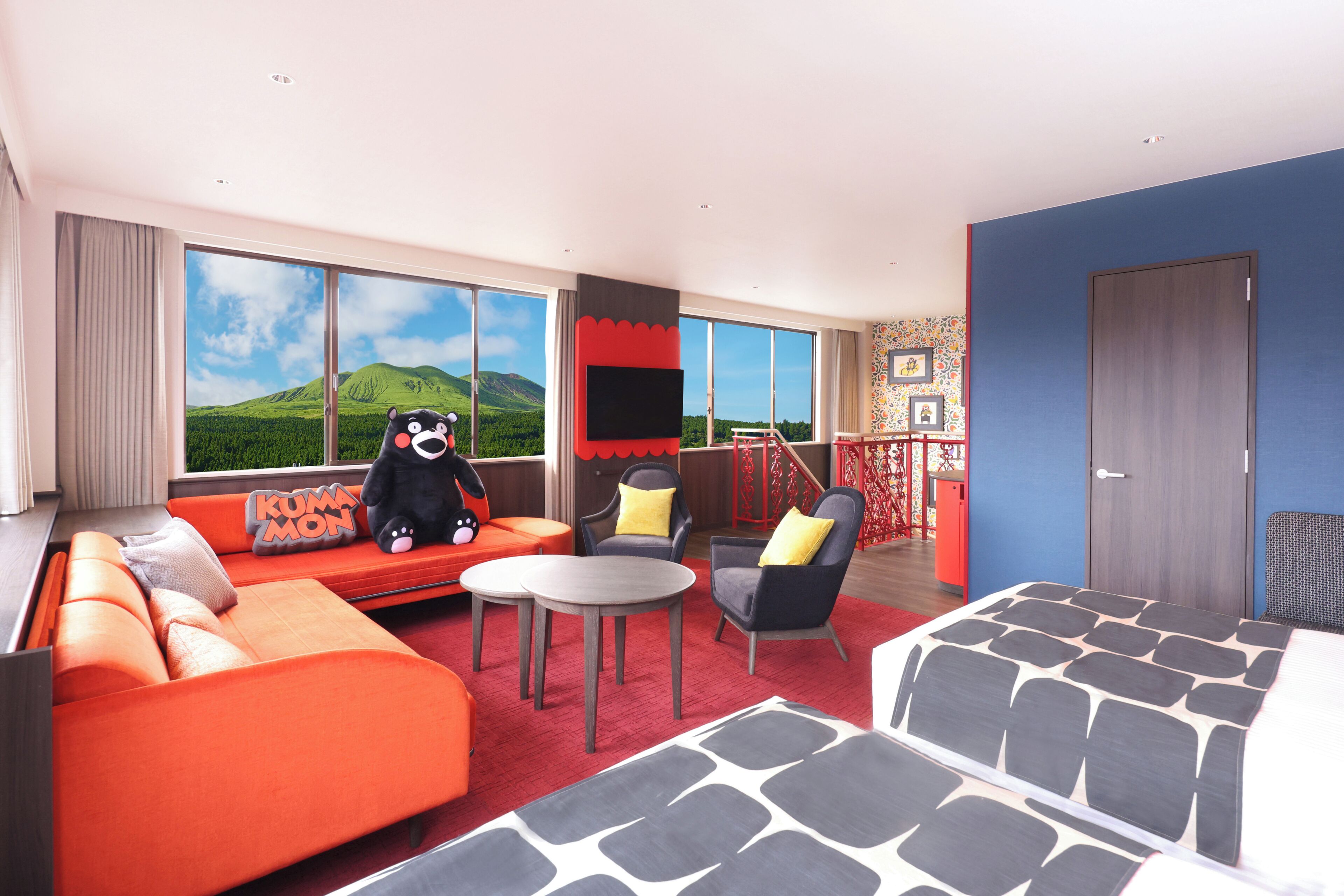 A modern hotel room with a large window, orange sofa, grey armchair, and a small table.
