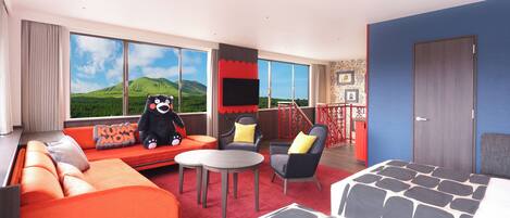 A modern hotel room with a large window, orange sofa, grey armchair, and a small table.