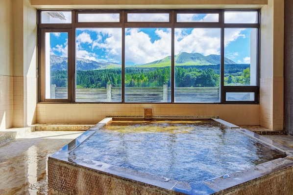 A hot tub with a view of mountains and forest through large windows. - Kamenoi Hotel Aso Park Resort (Aso)