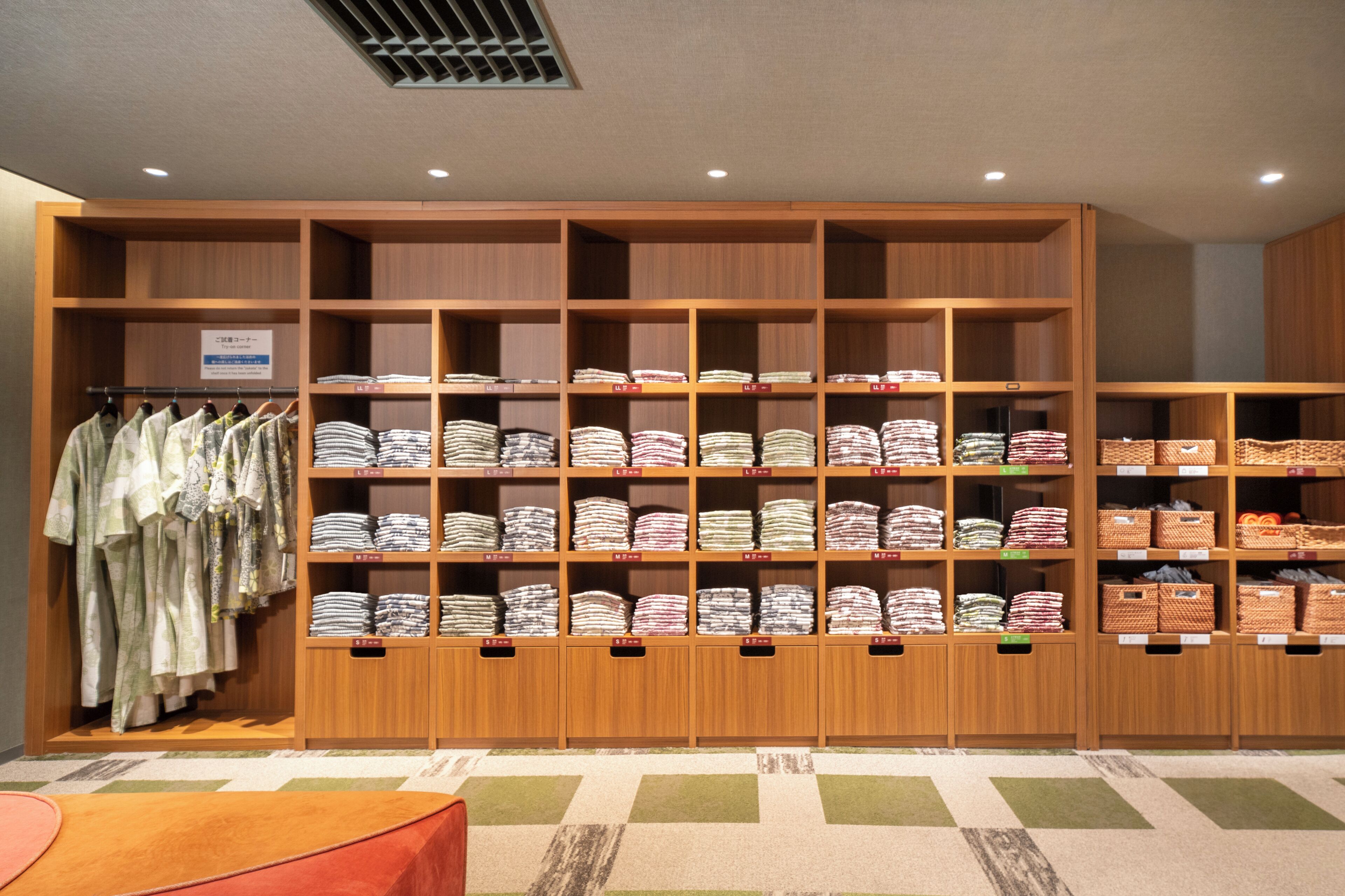 A clothing store with shelves of folded garments and a rack of hanging clothes.