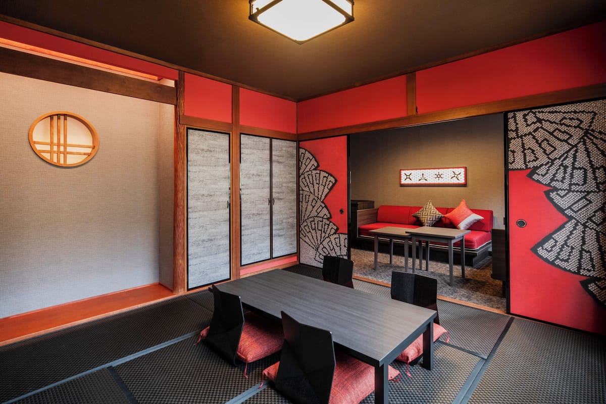 A traditional Japanese-style room with tatami flooring, a low table, and a red sofa.