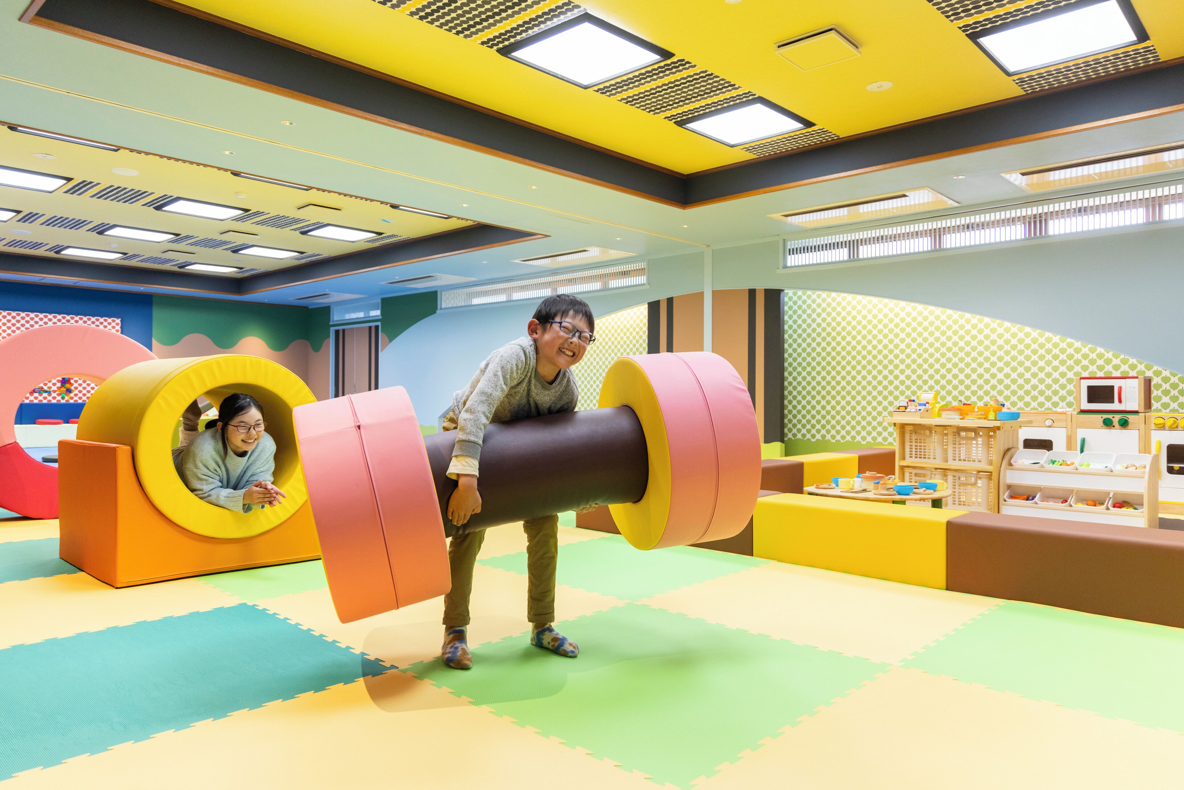A play area with colorful play structures and a large cylindrical object.